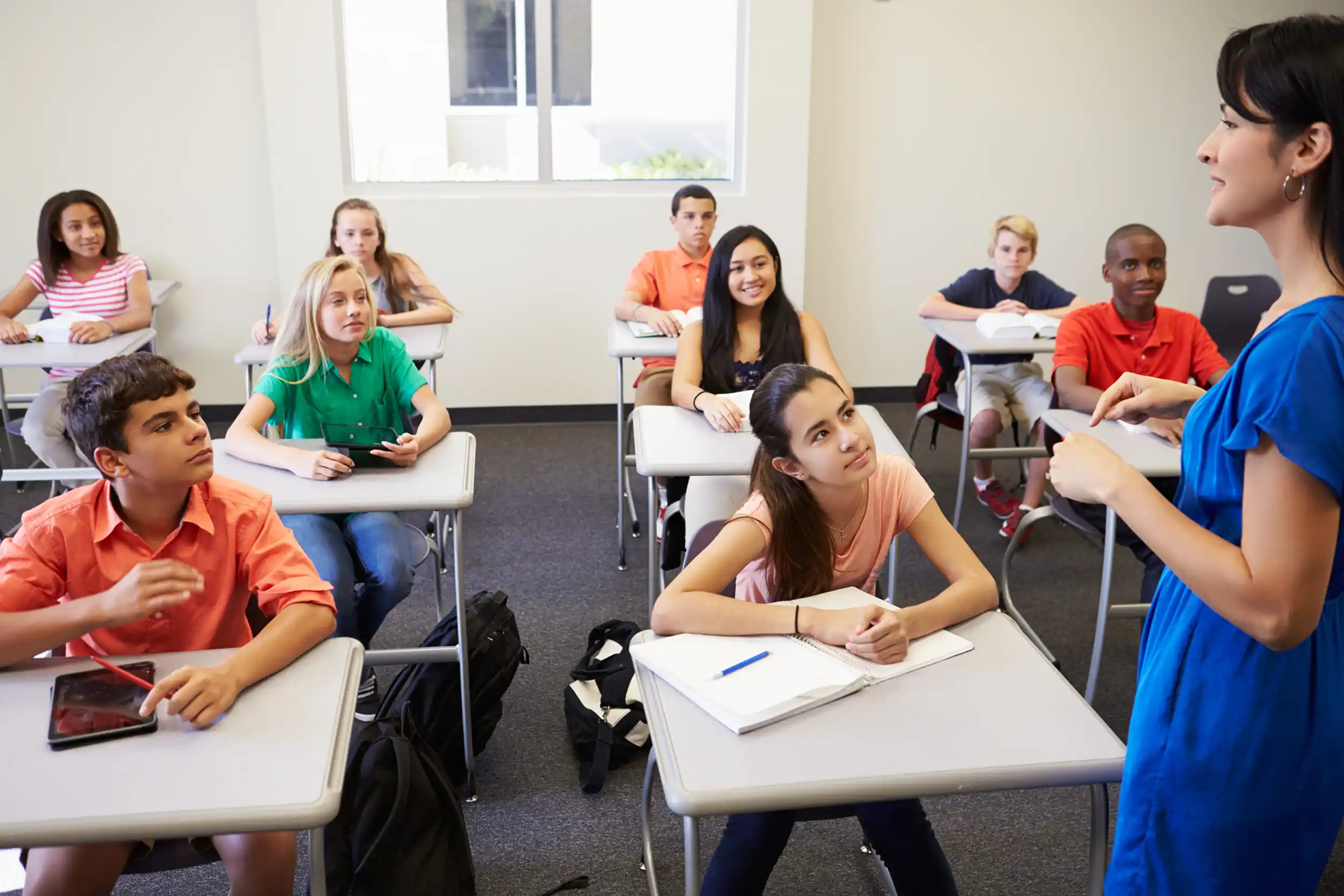 An image of a teacher and the head of the class, interested students looking on